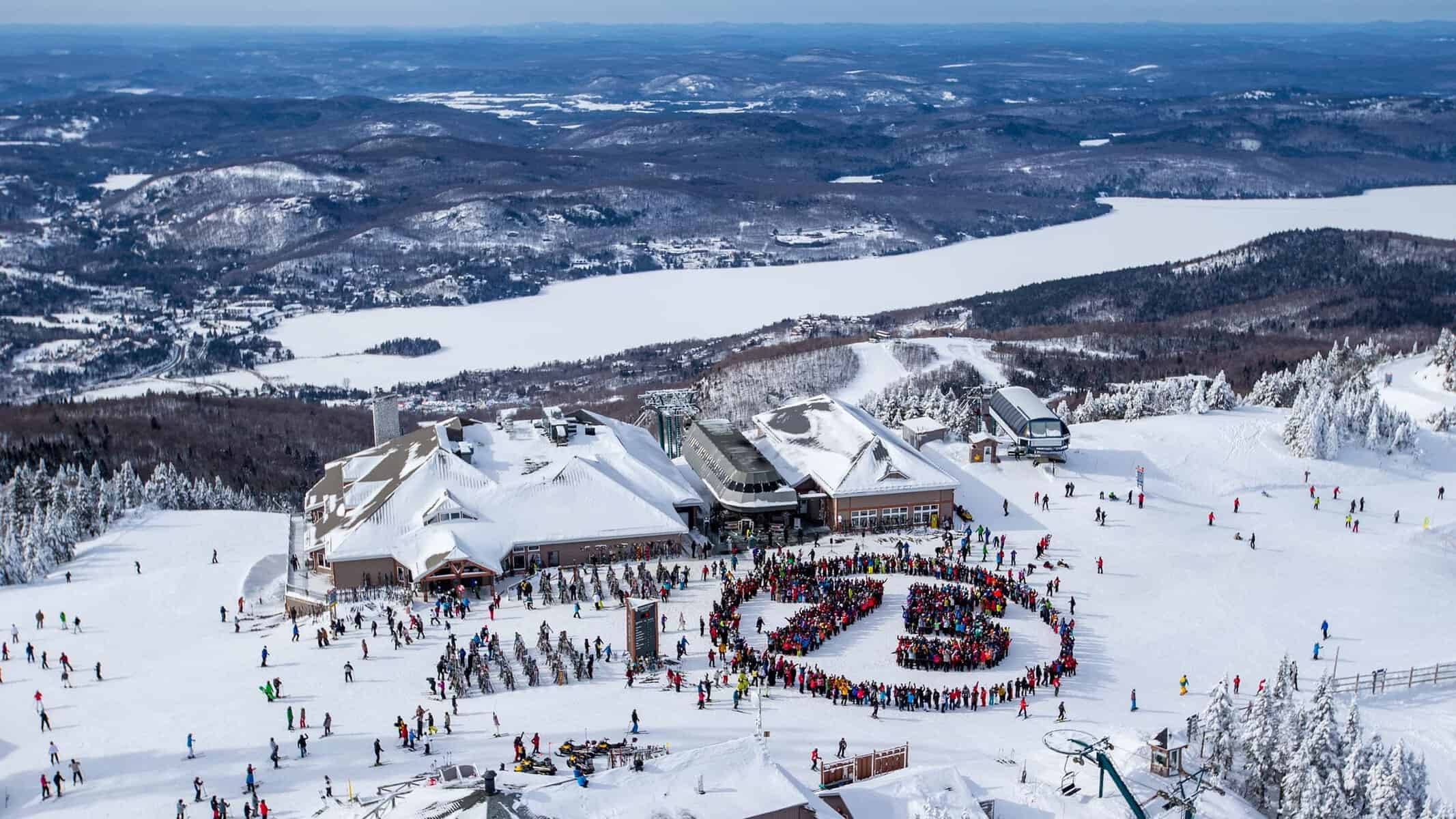 Cercle formé par des skieurs et des bâtiments enneigés sur la montagne Tremblant.