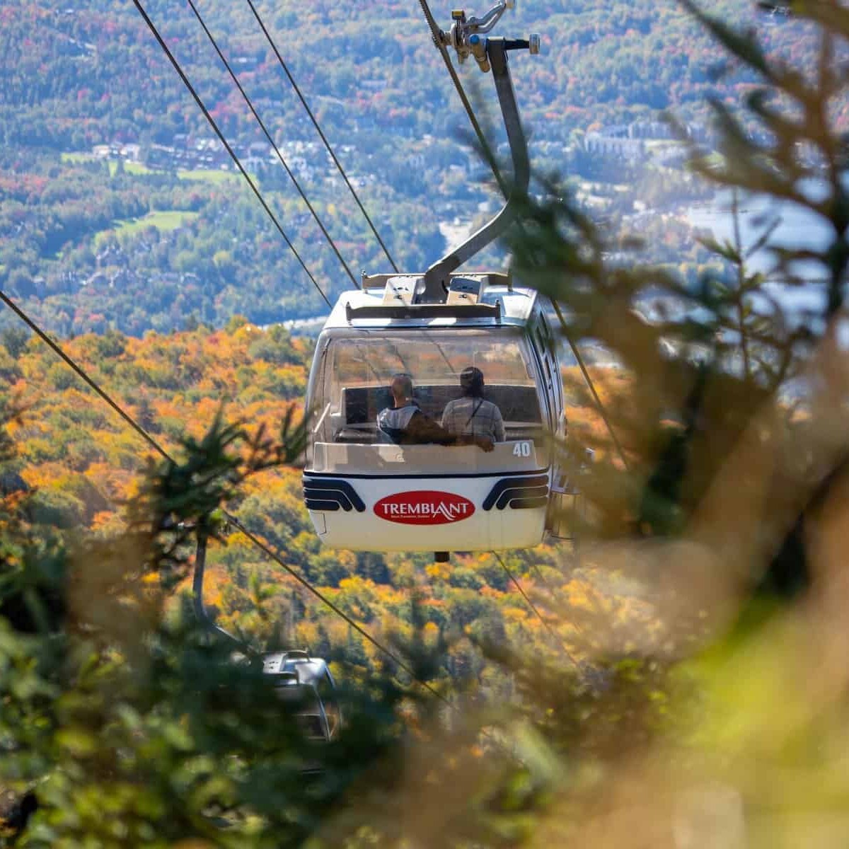 Cable car in Tremblant over colorful autumn forest landscape.