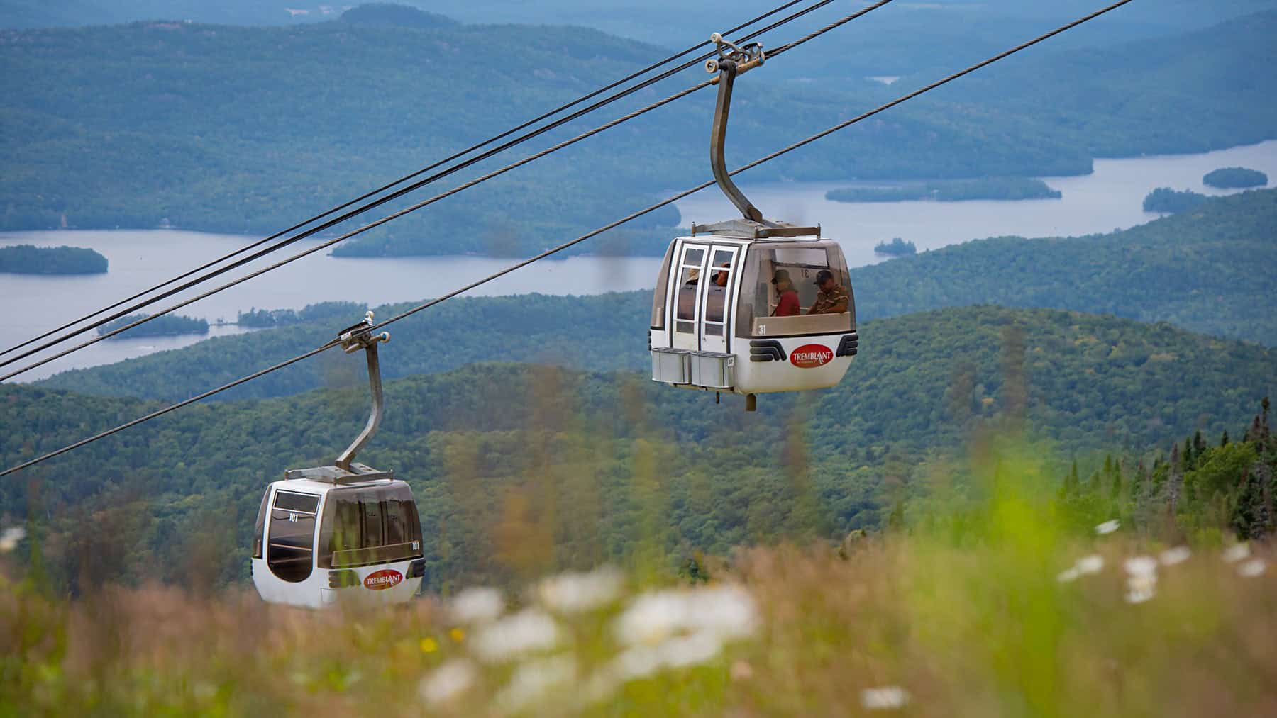 Tremblant gondola cable cars over lush green landscape and lake.