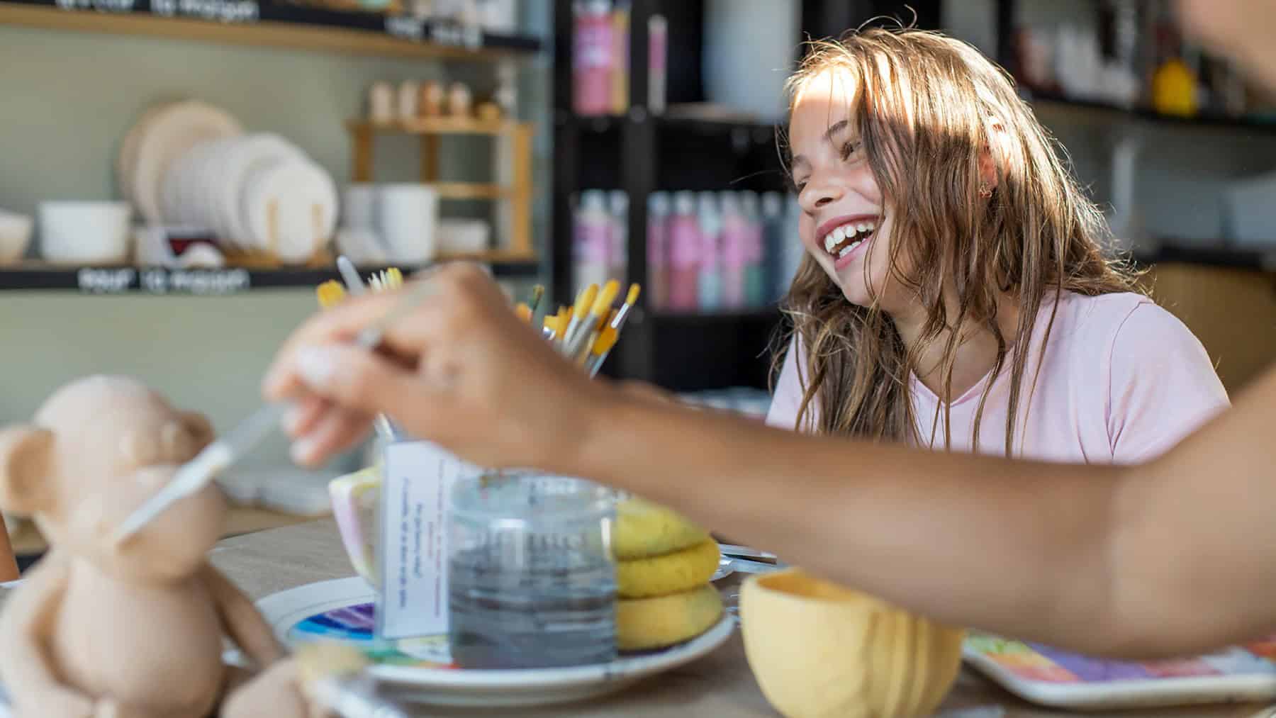 Young girl painting with brushes in an art studio setting.