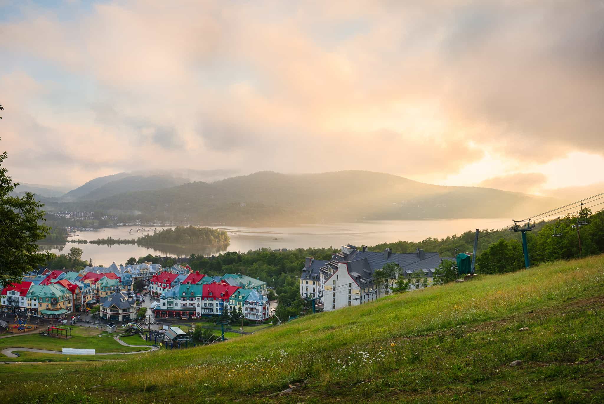 Paysage de Tremblant avec maisons colorées et montagnes au coucher du soleil.