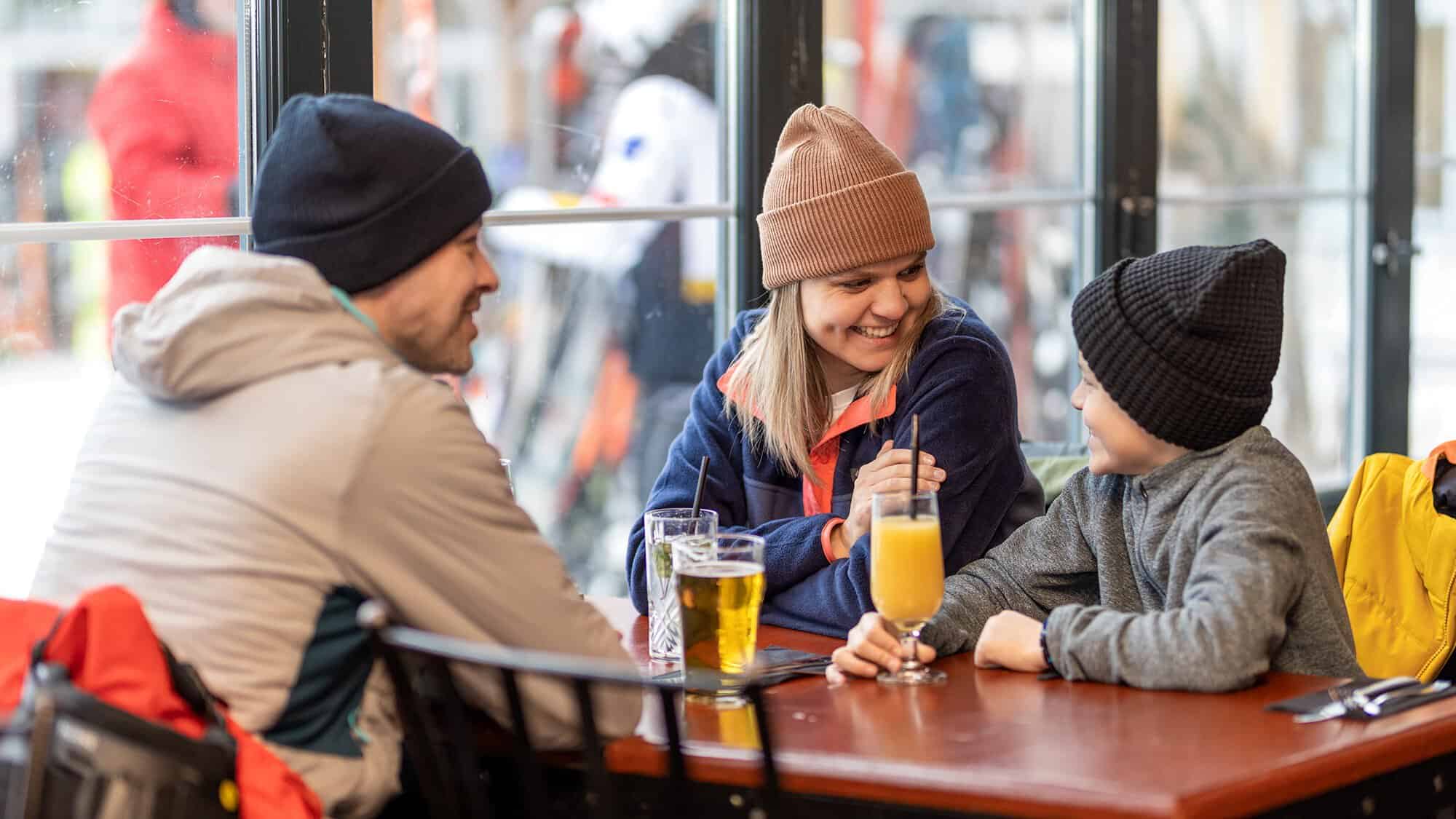 Groupe souriant buvant des boissons chaudes et froides autour d'une table.