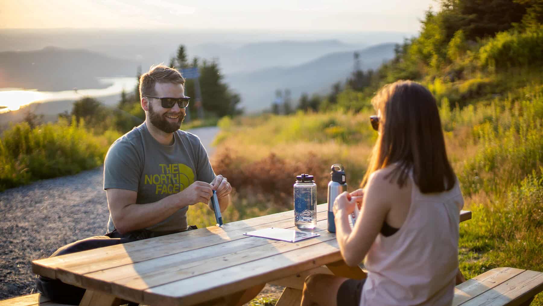 Couple enjoying a hillside picnic with mountains in the background at Tremblant.