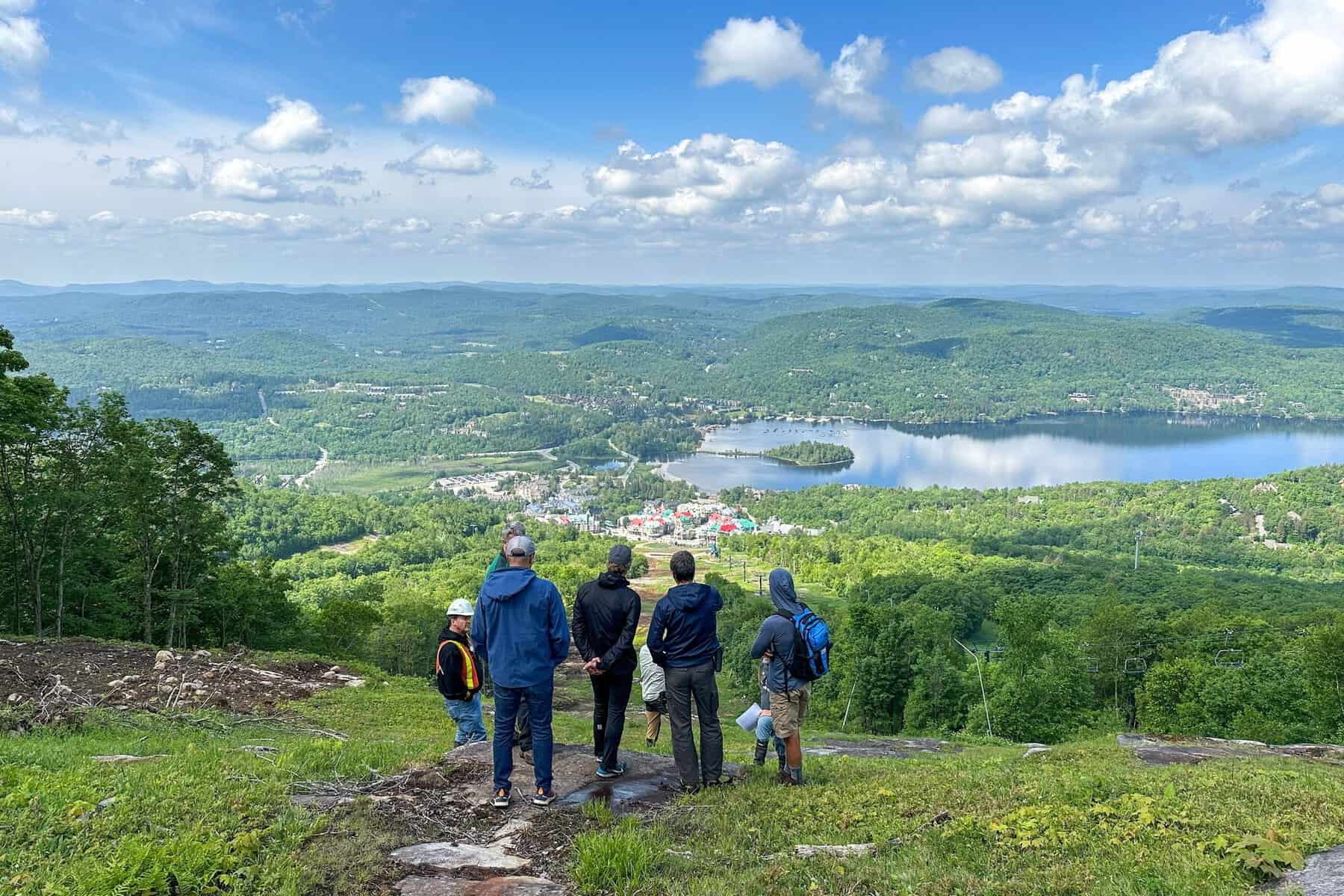 Groupe de randonneurs regardant le paysage vallonné et le lac au loin.