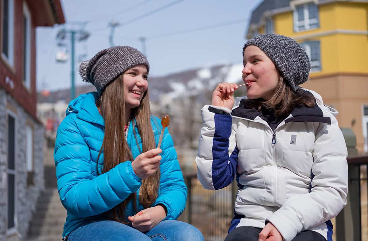 Deux femmes souriantes dégustant des sucettes en après-ski à Tremblant.