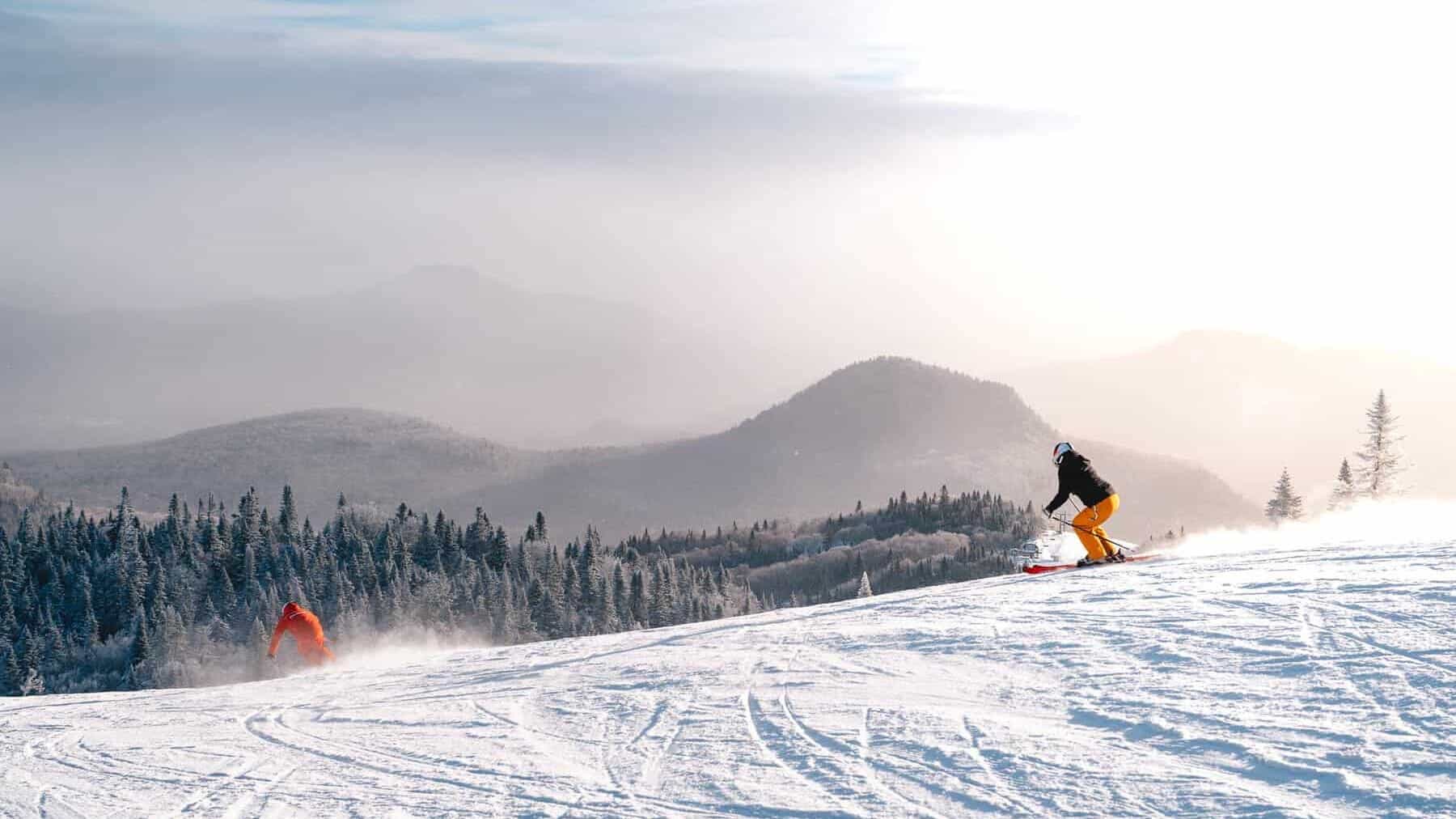 Skieur dévalant une pente enneigée au Mont Tremblant lors d'un ciel lumineux.