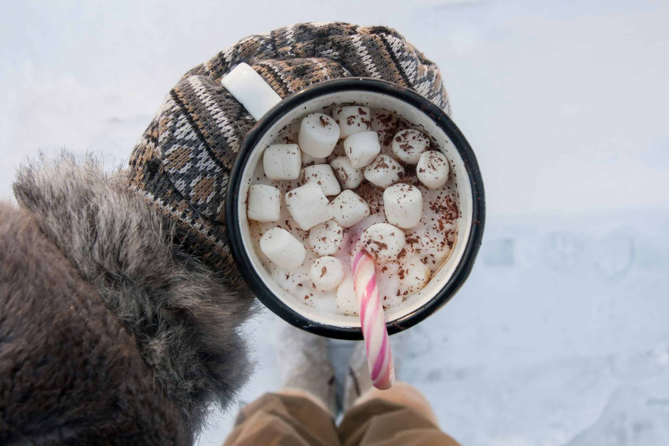 Tasse de chocolat chaud avec guimauves et bonbon dans la neige.
