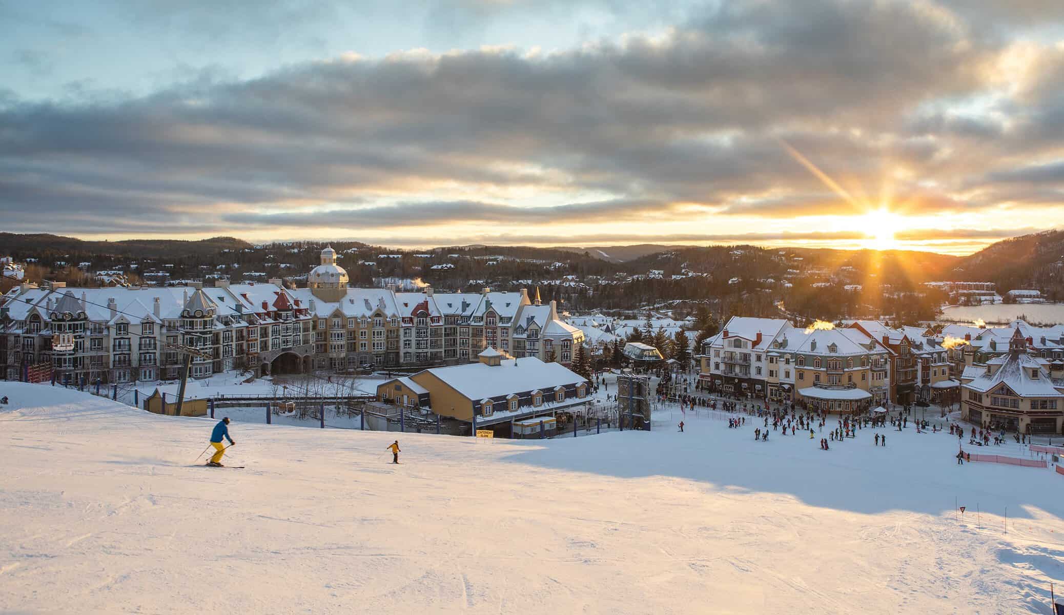 Pente enneigée près de Mont-Tremblant au coucher du soleil avec skieurs.