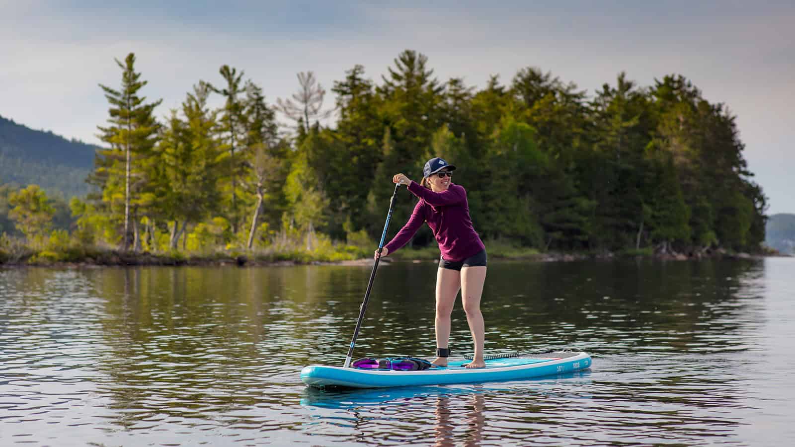 Femme faisant du paddleboard sur le lac Tremblant en nature.