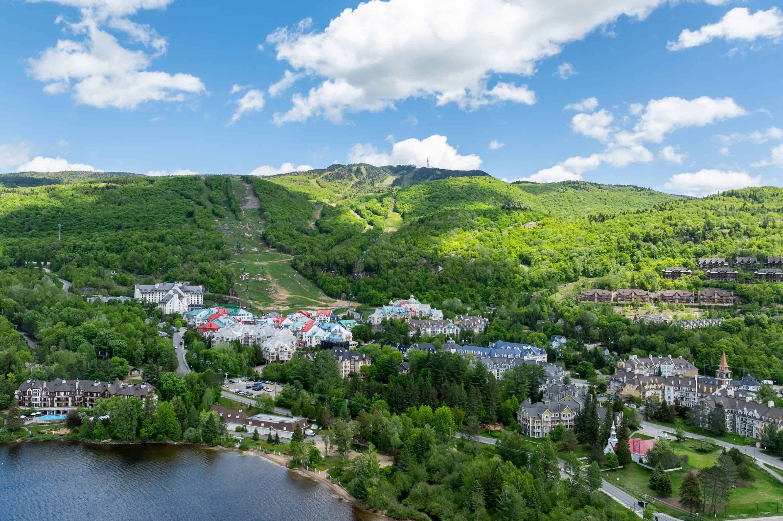 Vue panoramique du village de Tremblant entouré de montagnes verdoyantes.