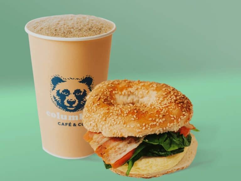 Sandwich bagel avec bacon, légumes et boisson chaude.