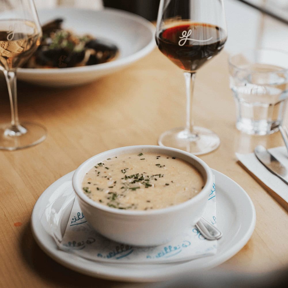 Creamy soup served with wine in a cozy restaurant setting.