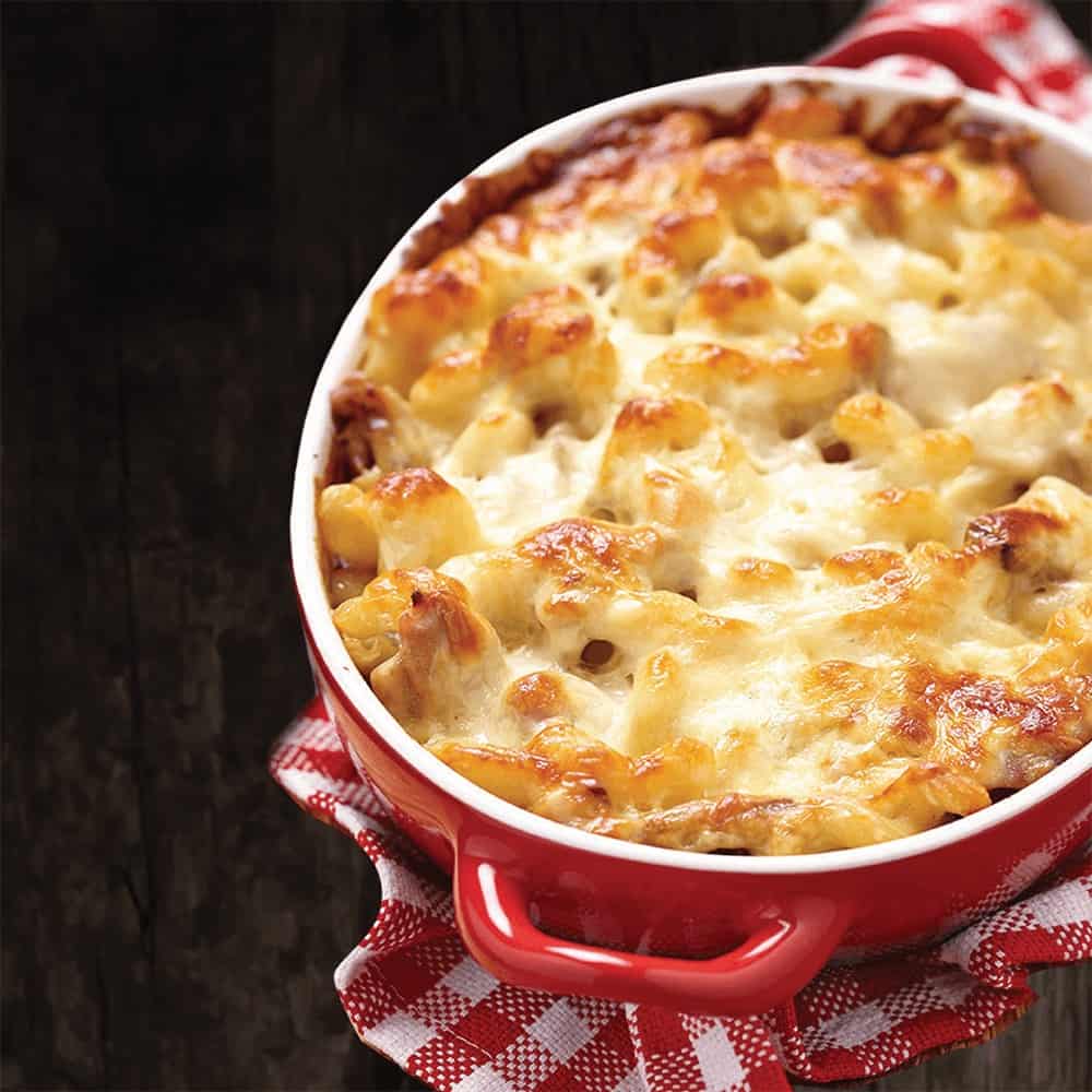Baked mac and cheese in a red dish with golden cheese topping.