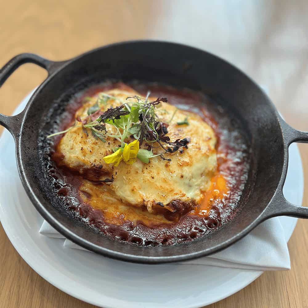 Hearty baked dish with herbs and melted cheese in a cast-iron skillet.