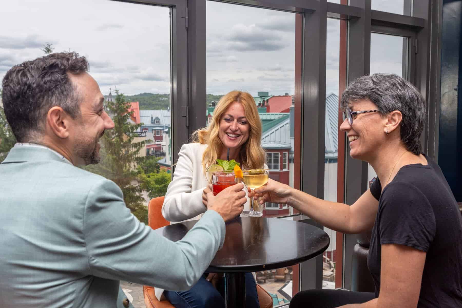 Trois professionnels trinquent sur une terrasse avec vue panoramique.