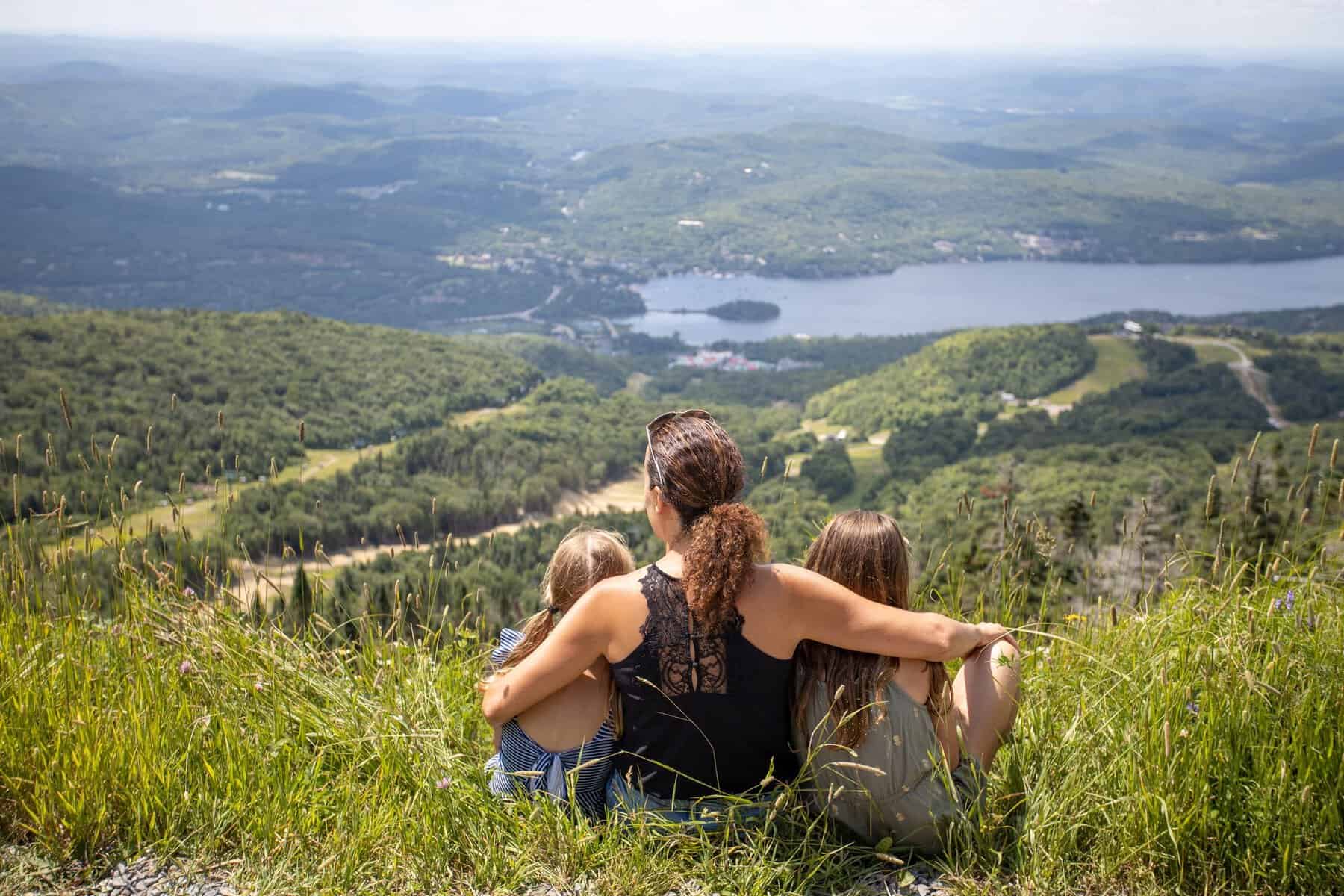 Famille assise ensemble sur un spectacle panoramique du mont Tremblant, vue sur les lacs et les vall.