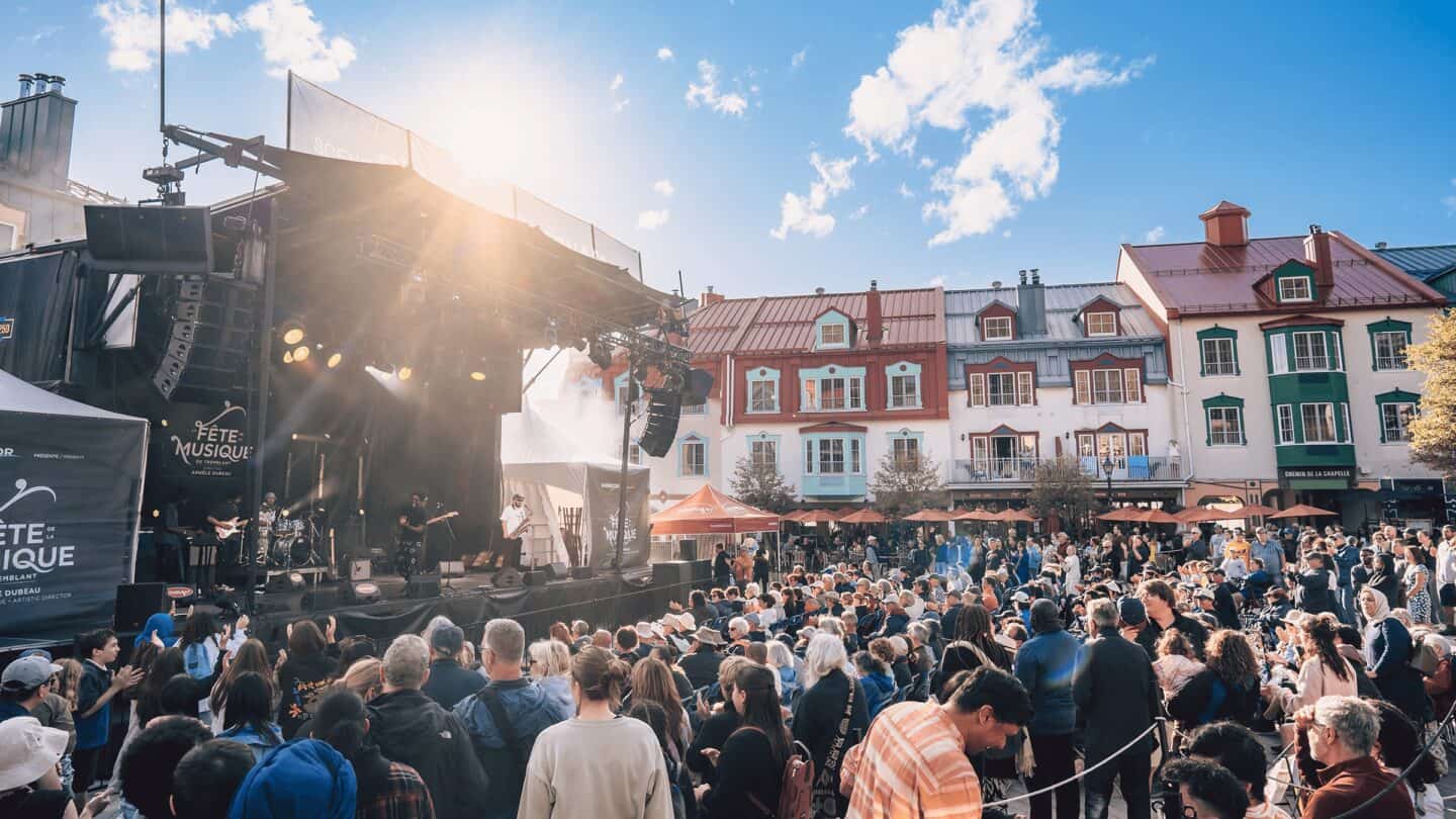Crowd at outdoor Tremblant festival during sunny day with stage performance.