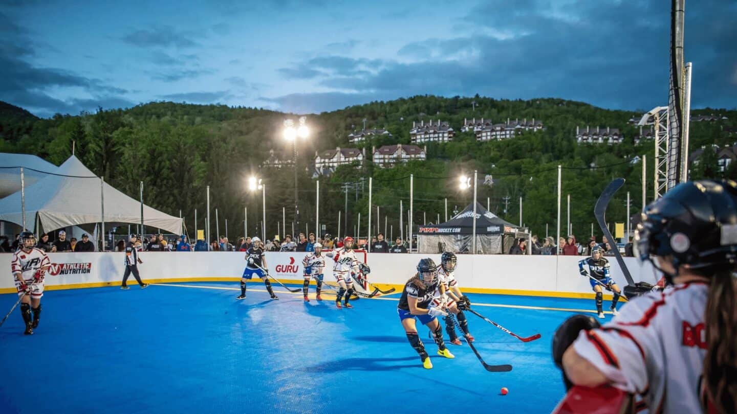 Outdoor roller hockey game under evening lights at Tremblant with players in action.
