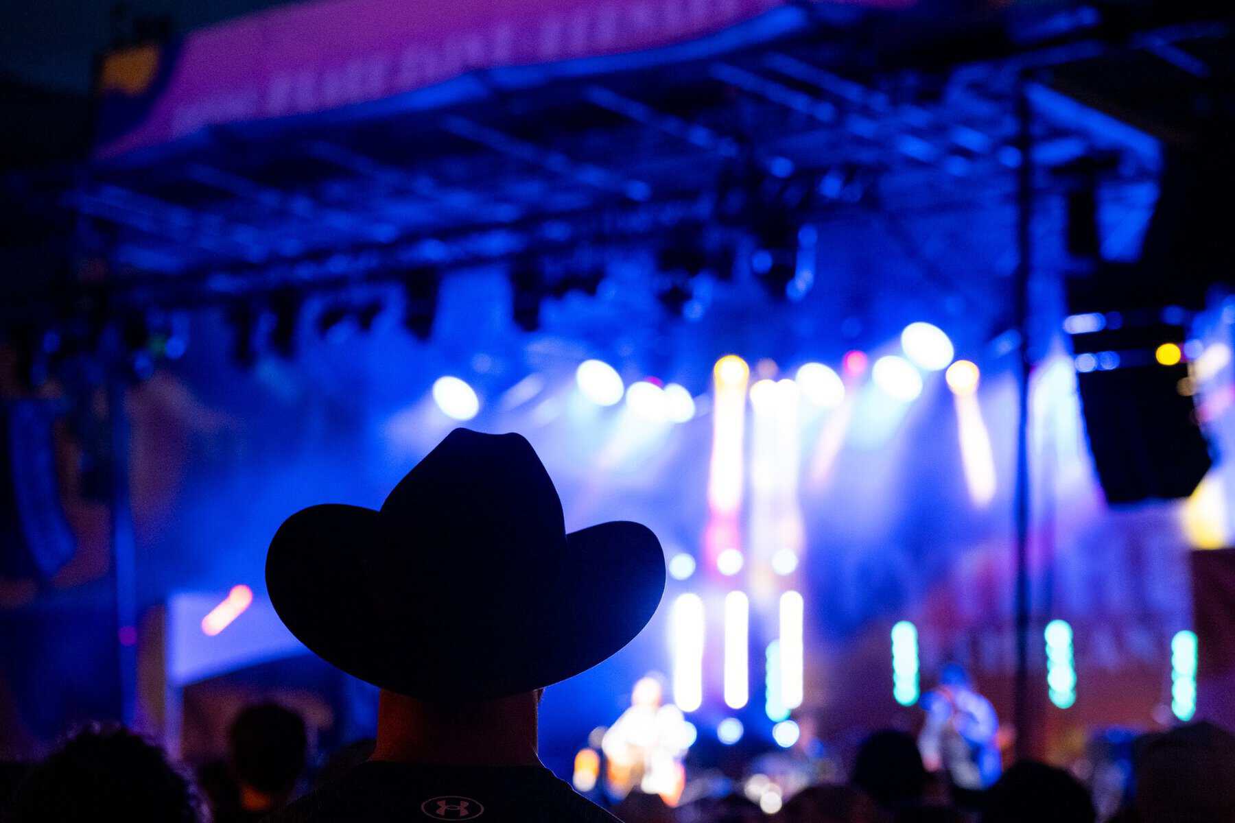 Spectateur portant chapeau de cowboy lors d'un concert à Tremblant en soirée.