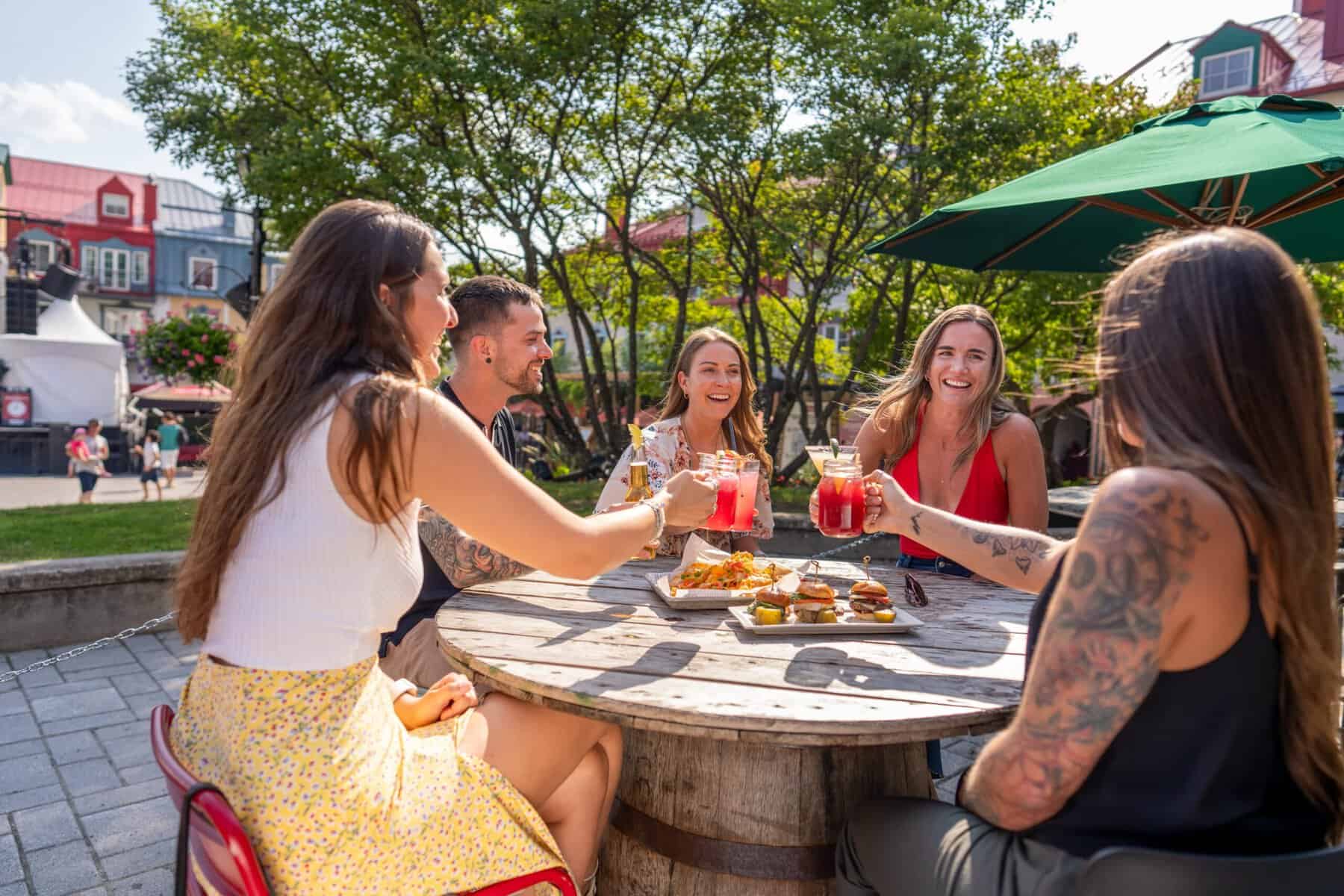 Groupe d'amis trinquant autour d'une table en terrasse extérieure.