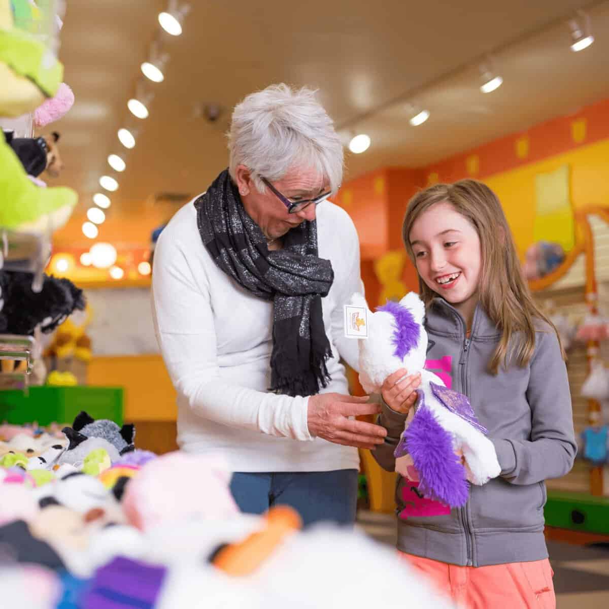 Grandmother and girl choosing a plush toy together in a colorful store.