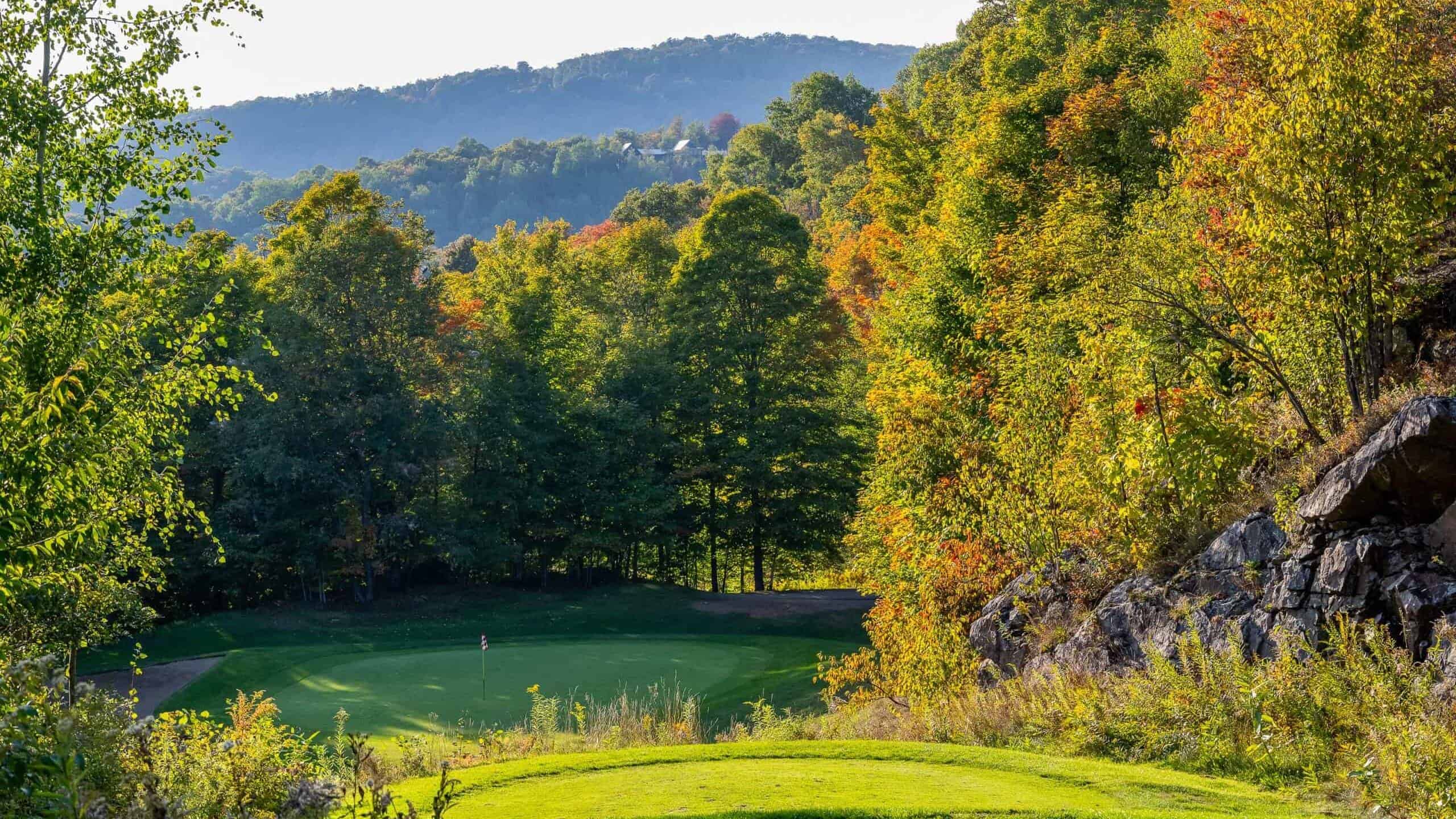 Scenic golf course in Tremblant surrounded by colorful autumn trees.