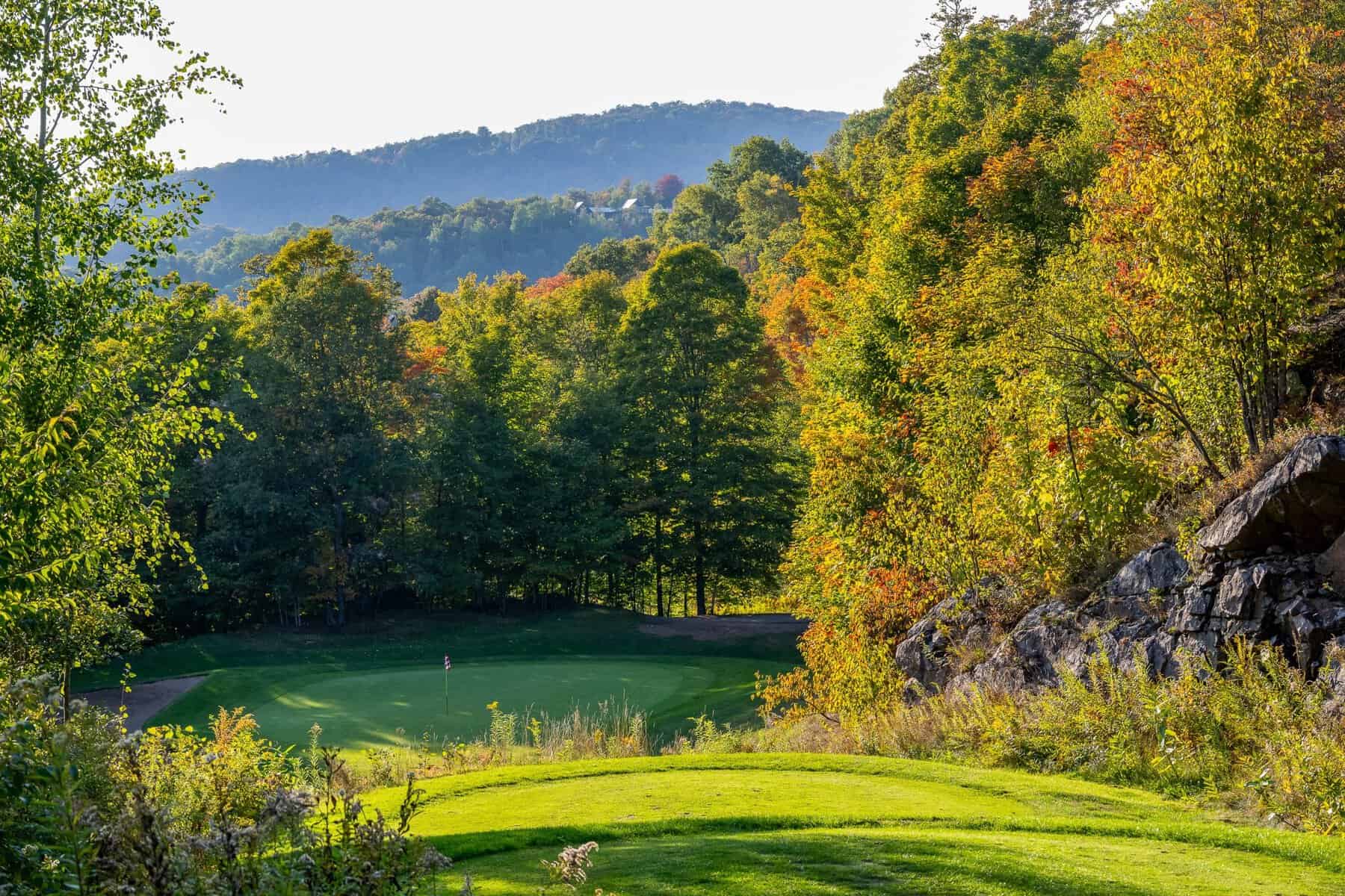 Golfeur à Tremblant sur parcours entouré d’arbres automnaux.