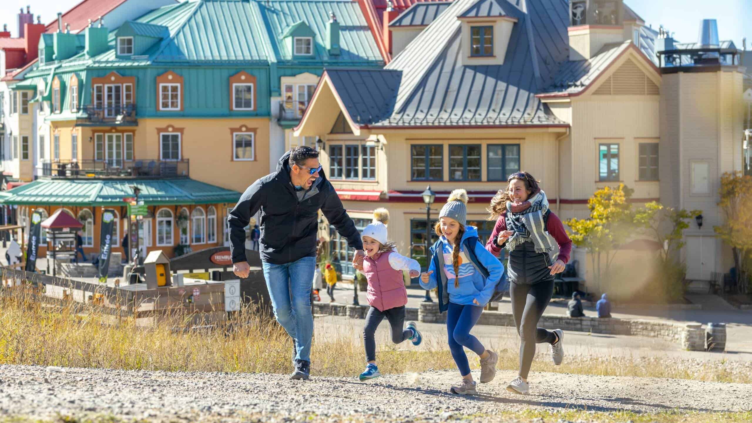 Famille profitant d'une promenade à Tremblant avec maisons colorées en arrière-plan.