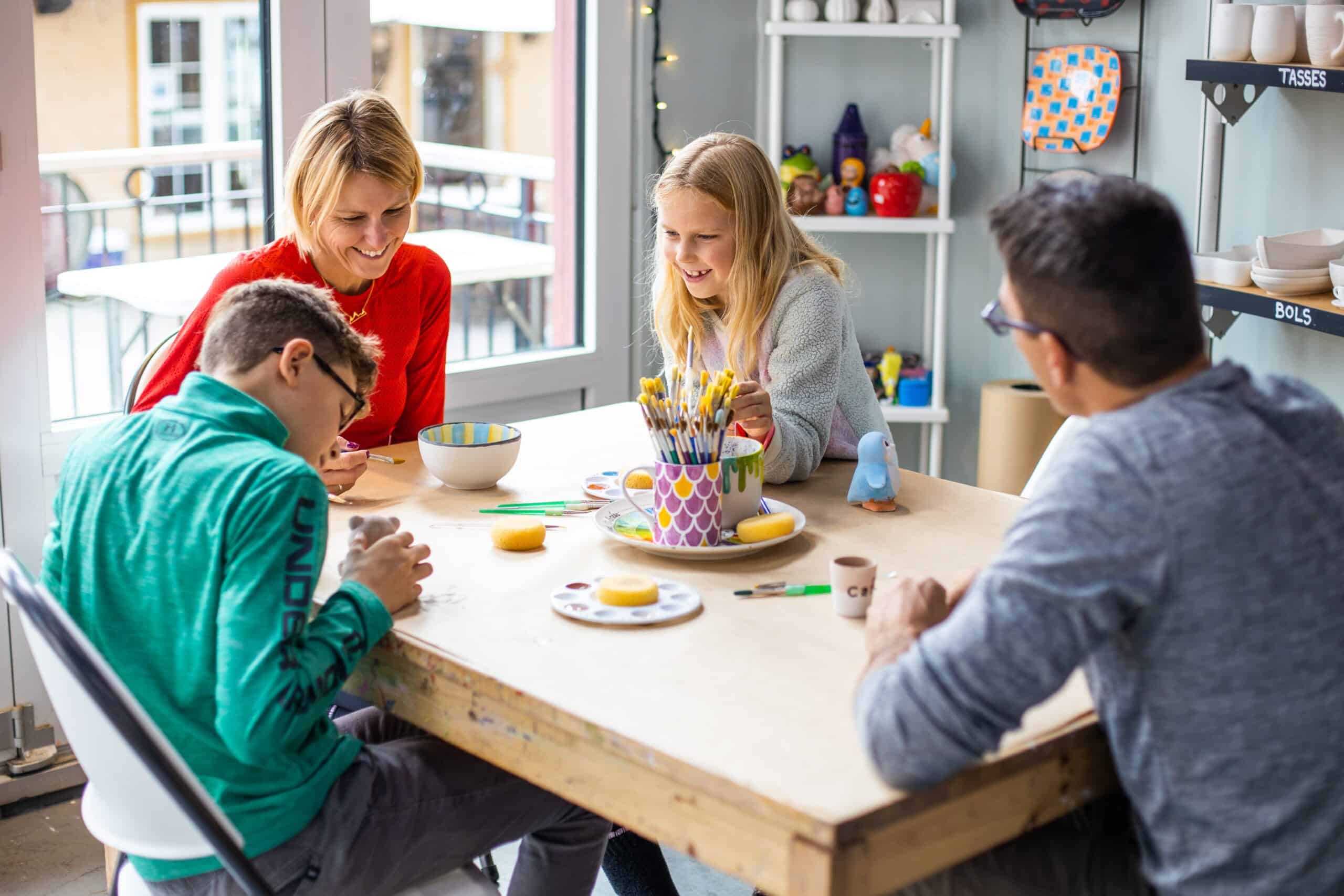 Enfants et adulte créant des objets d'art dans un atelier intérieur.