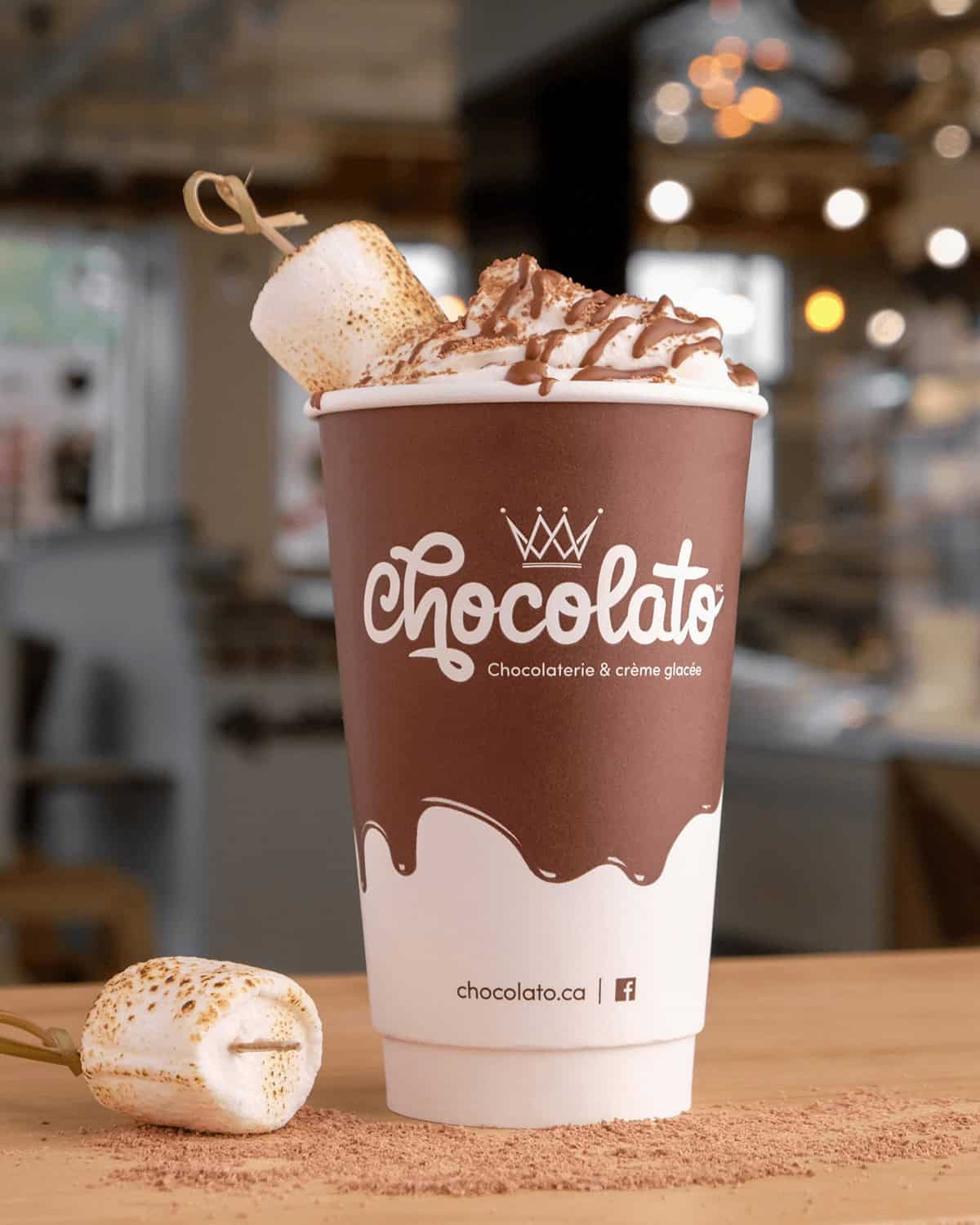 Chocolate hot chocolate with marshmallow and whipped cream in a takeaway cup.