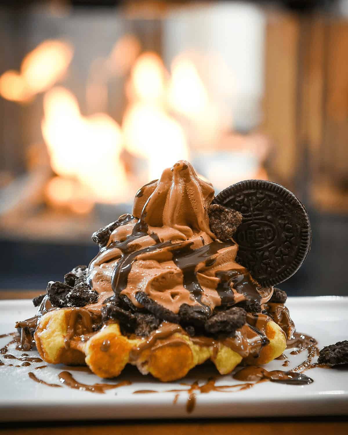 Delicious waffle topped with chocolate ice cream, Oreo cookies, and chocolate syrup.