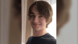 Portrait d'un jeune homme souriant près d'une porte.
