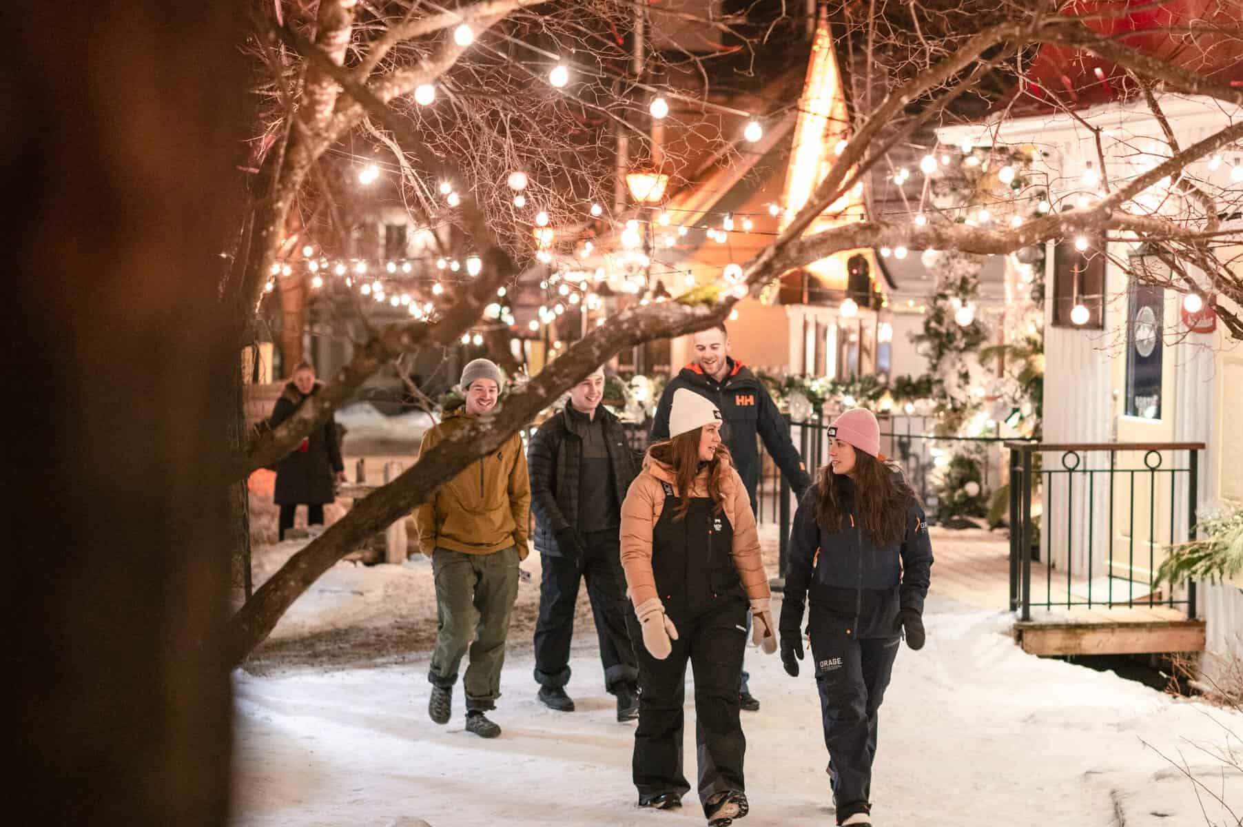 Groupe de personnes marchant dans une rue illuminée de Tremblant en hiver.