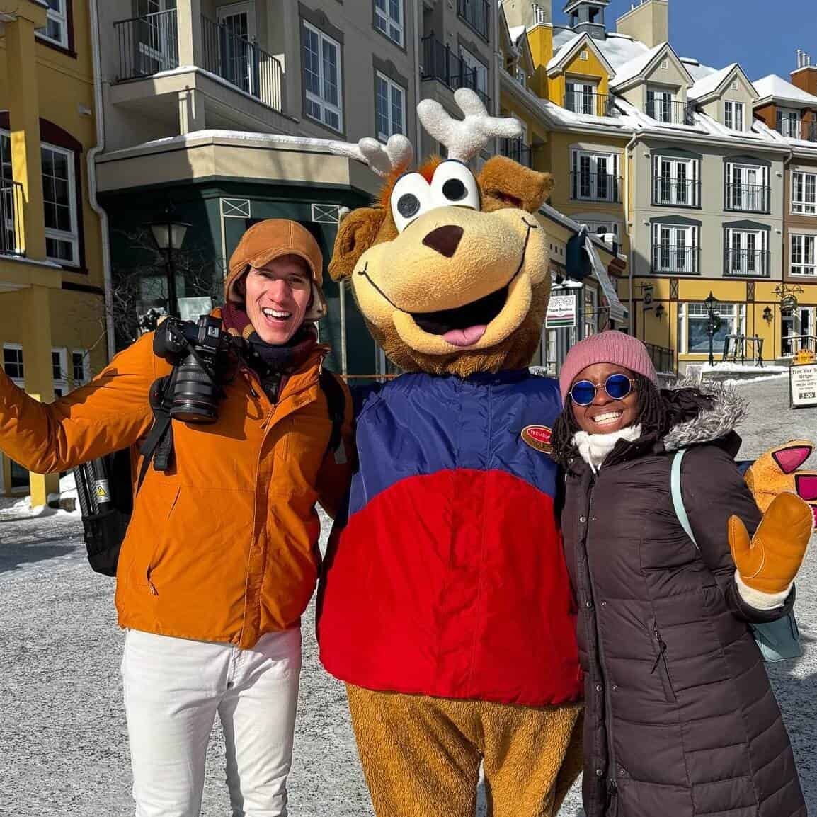 Happy couple with mascot in snowy Mont-Tremblant village.