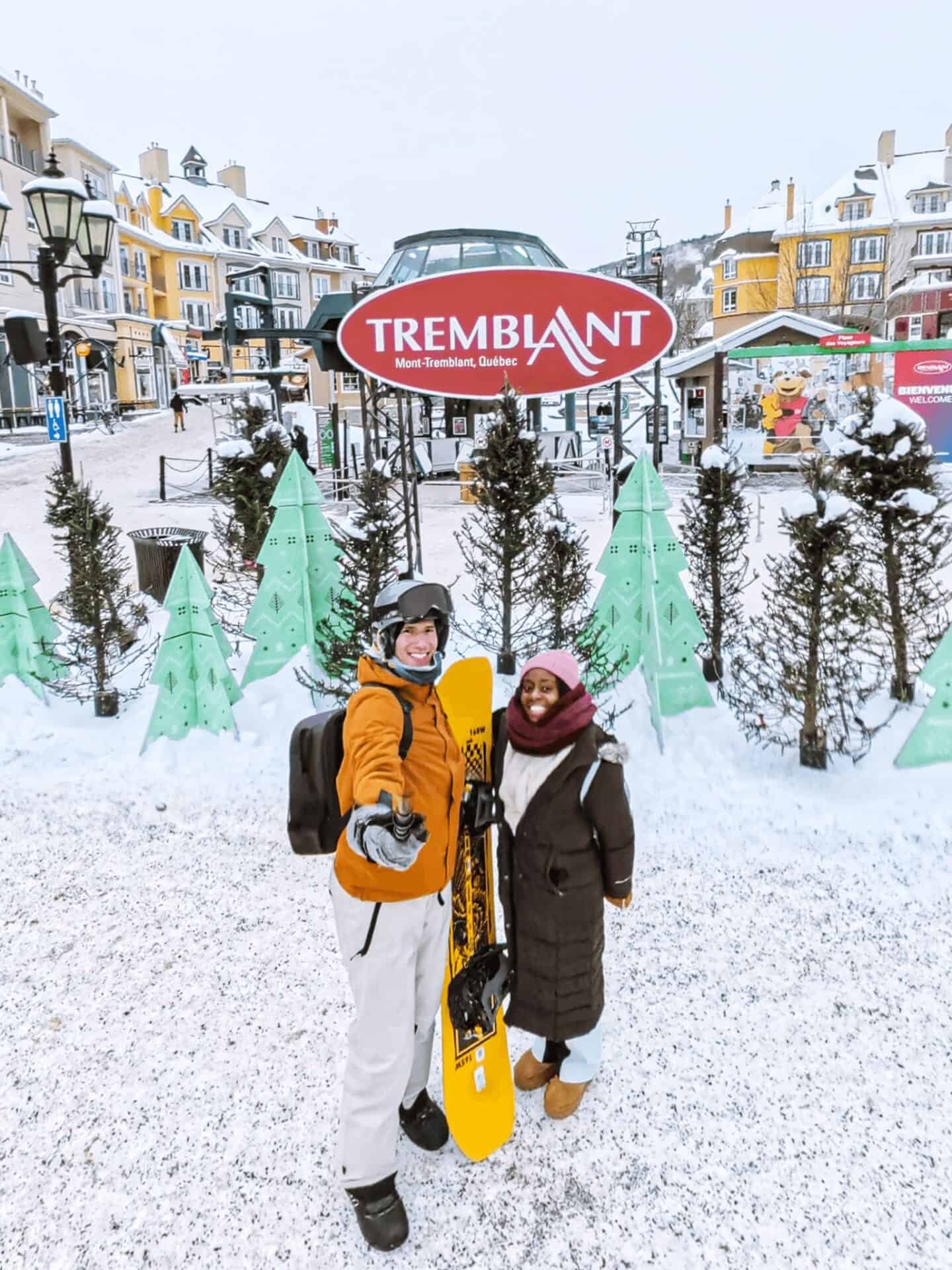Couple enjoying winter in Mont-Tremblant with snow-covered buildings and trees.