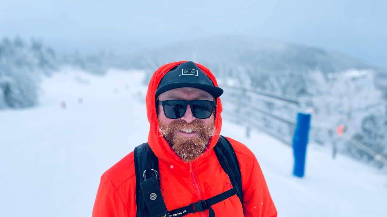 Homme barbu portant casque et lunettes de soleil dans un paysage de neige Tremblant.