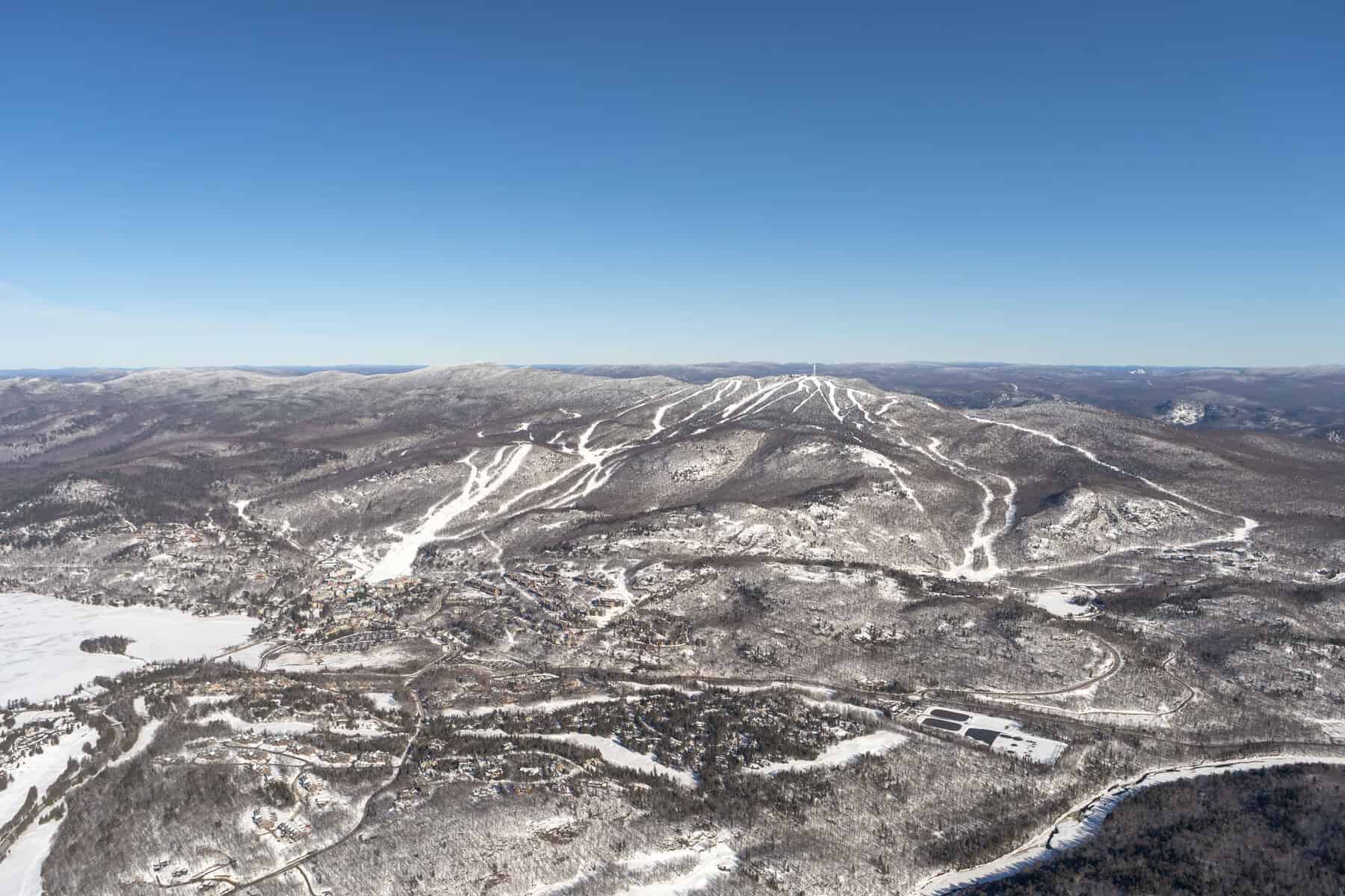 Snow-covered mountain slopes and clear blue sky at Mont-Tremblant hills.