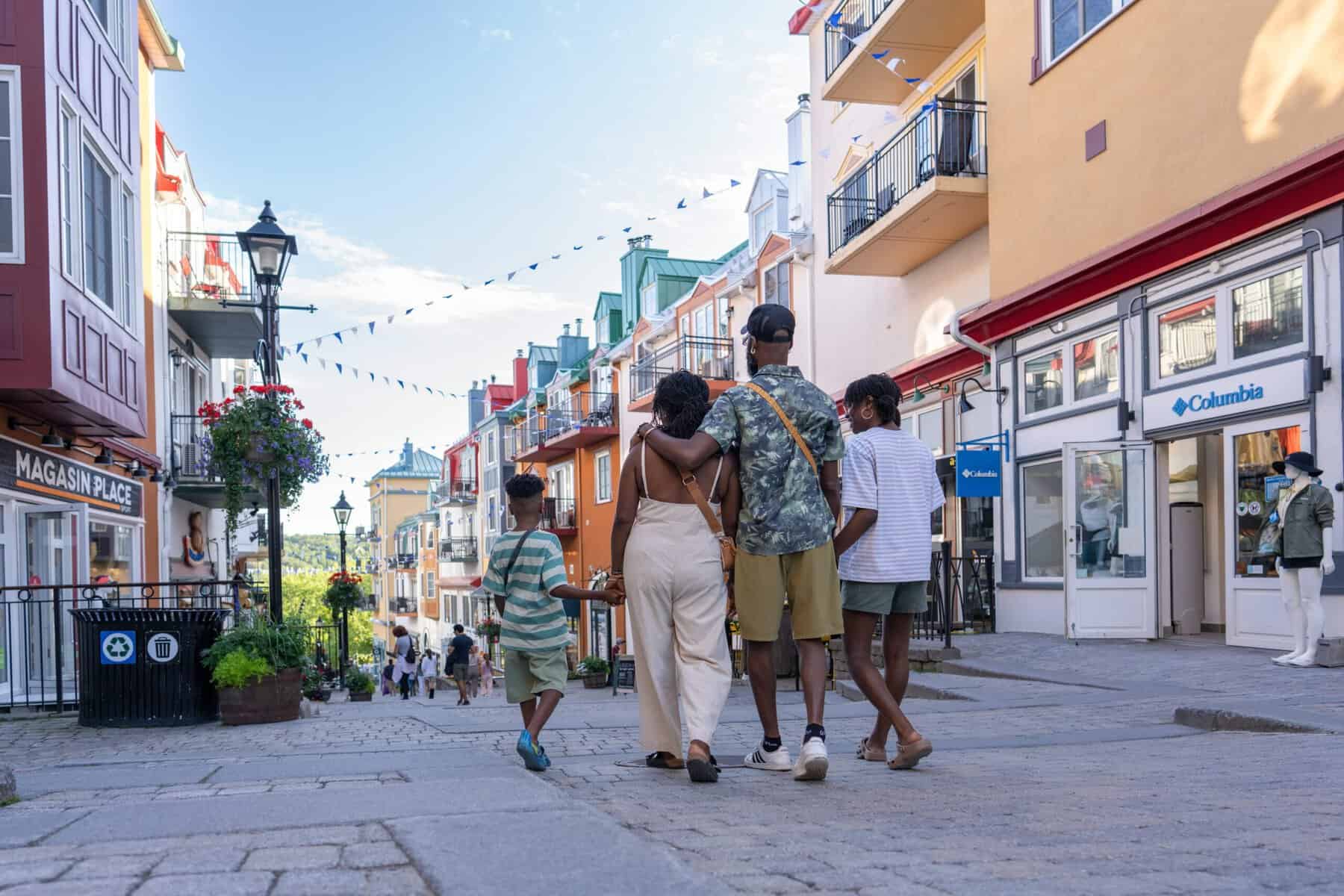 Family walking together on a pedestrian street in Tremblant village under string lights.