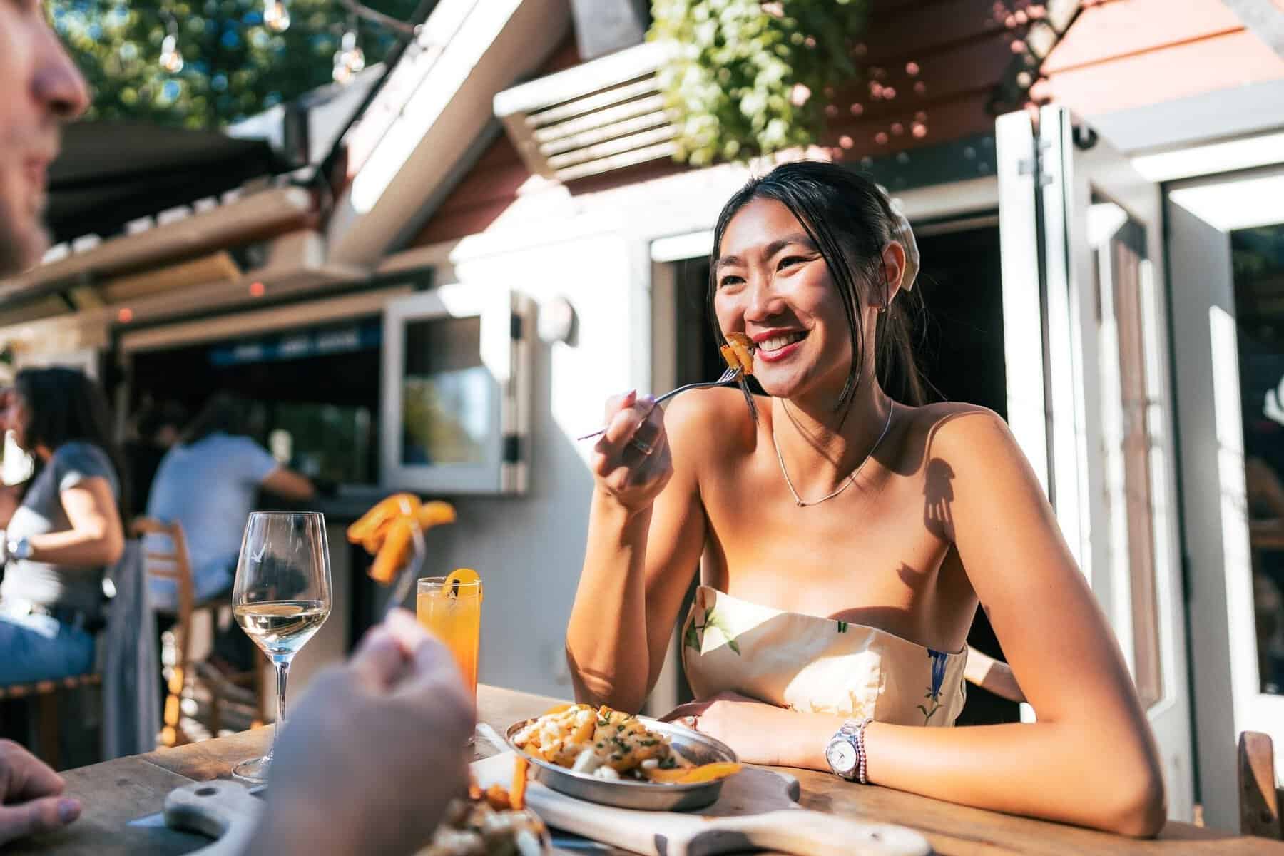 Sourire d'une femme dégustant un repas en terrasse au Tremblant.
