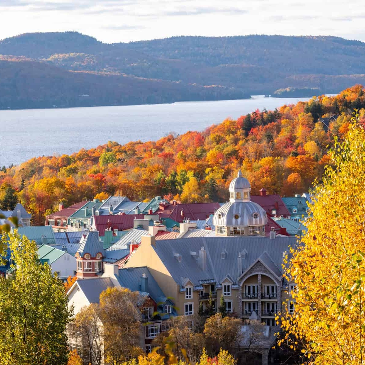 Scenic Tremblant village surrounded by autumn trees and lake.