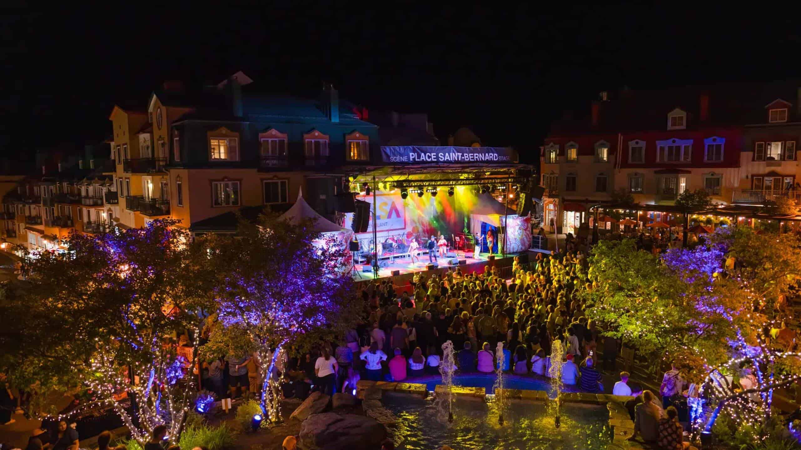 Nighttime outdoor concert at Tremblant with colorful lights and large audience.