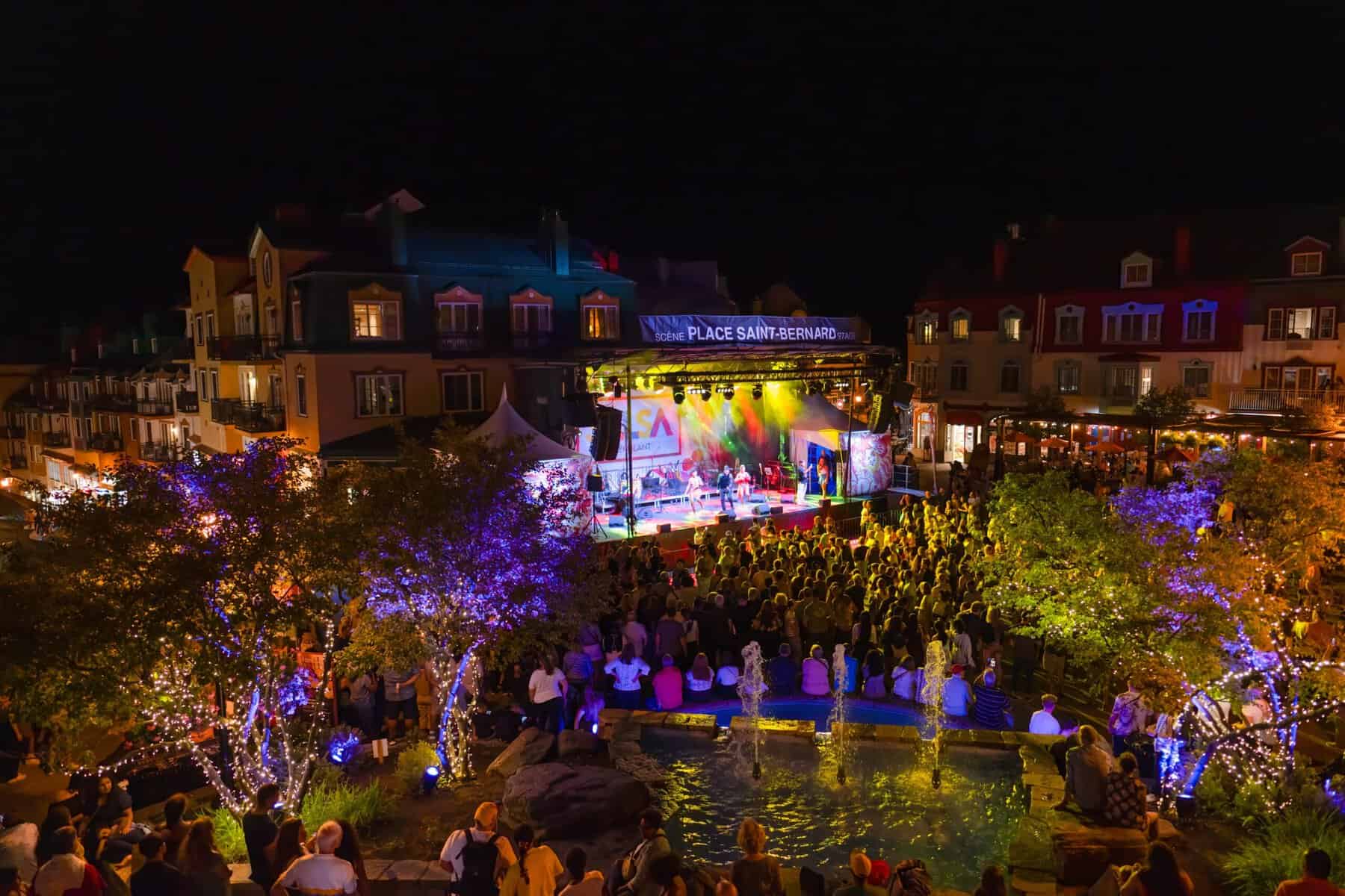 Scène de concert en plein air au festival Salsa Tremblant, village piétonnier illuminé.