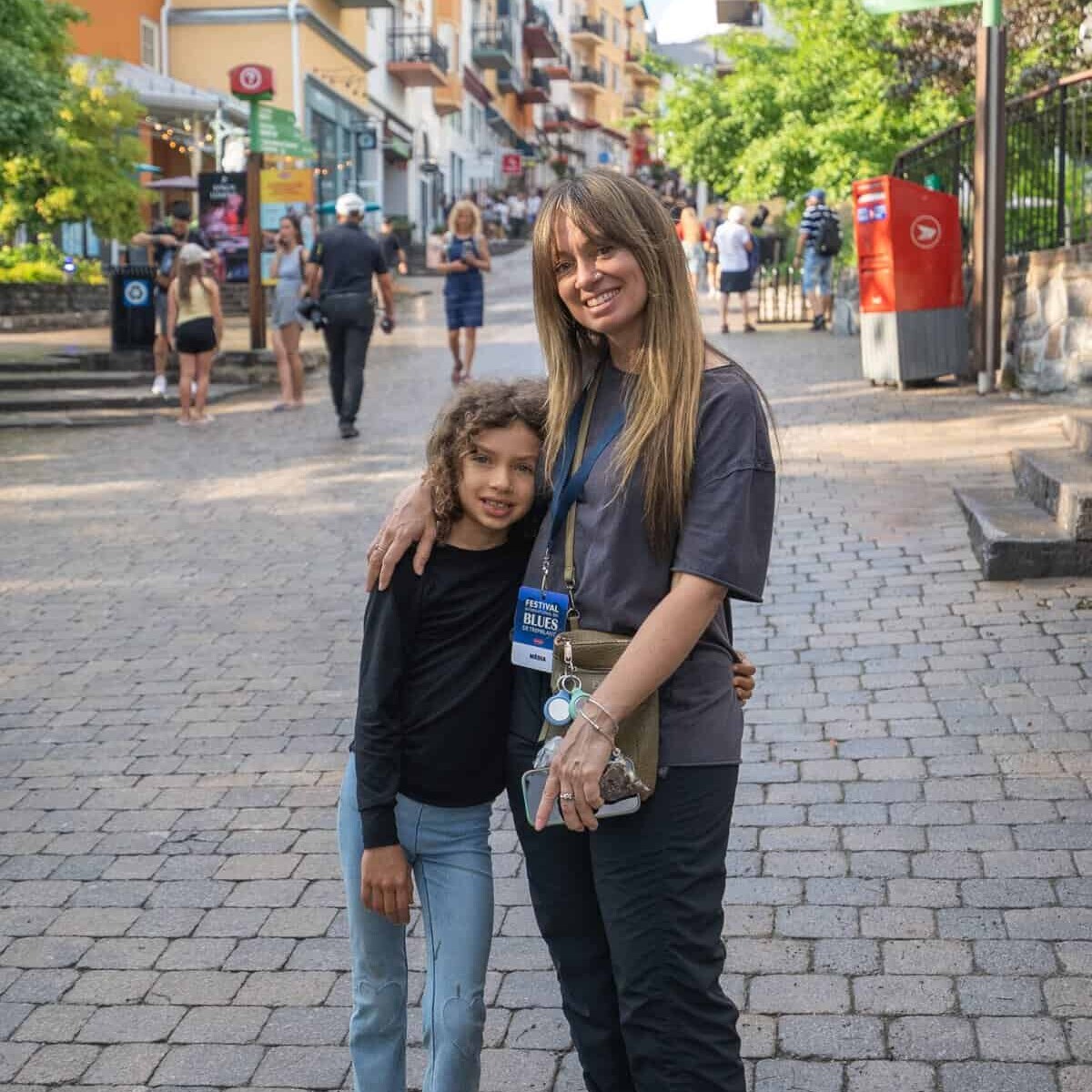 Famille souriante dans une rue pav&eacute;e anim&eacute;e de Tremblant.