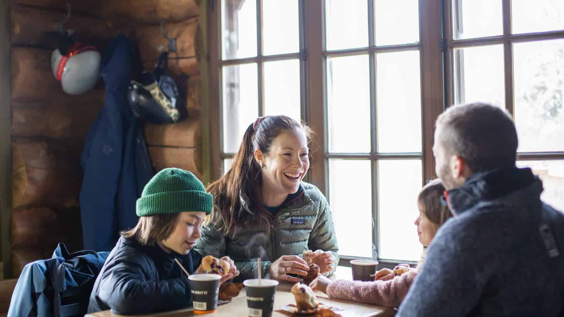 Family enjoying hot drinks and snacks at a cozy lodge cafe in Tremblant.
