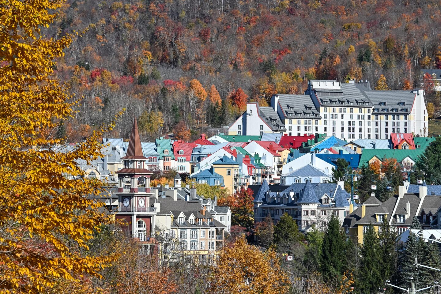 Panoramic view of Tremblant’s colorful village in autumn, surrounded by yellow and orange foliage.