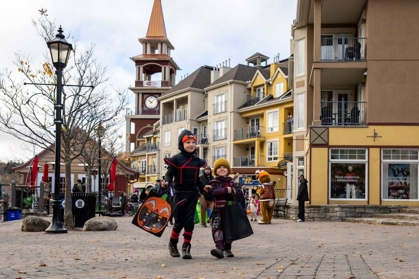 Children in costumes walking through Tremblant’s colorful village in an autumn setting.